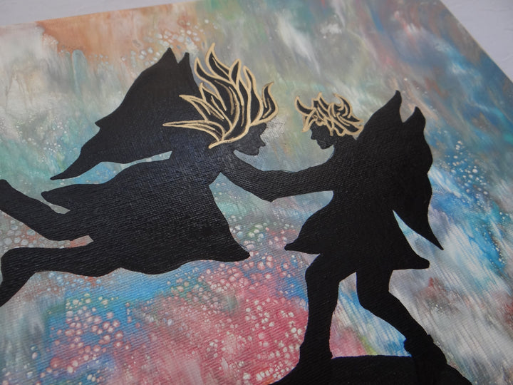 Close-up view of a 12"x12" acrylic pour painting featuring two silhouetted fairies with gold-accented hair, set against a dreamy, celestial abstract background. The fine details of the embellishments are highlighted.