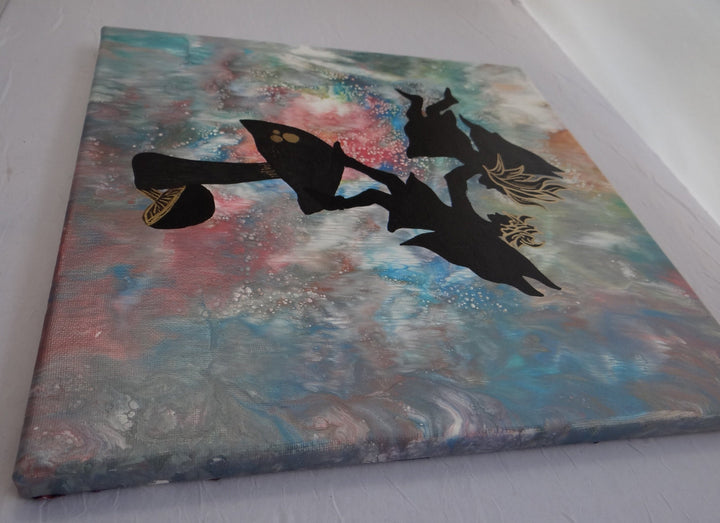 Side angle view of a 12"x12" acrylic pour painting featuring silhouetted fairies with gold accents standing on a mushroom against a celestial, multicolored abstract background.