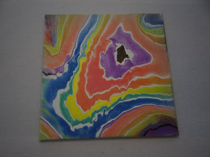 A 12"x12" acrylic pour painting featuring a vibrant geode-inspired rainbow design, created with iridescent color-shift paints by Blue St Designs.