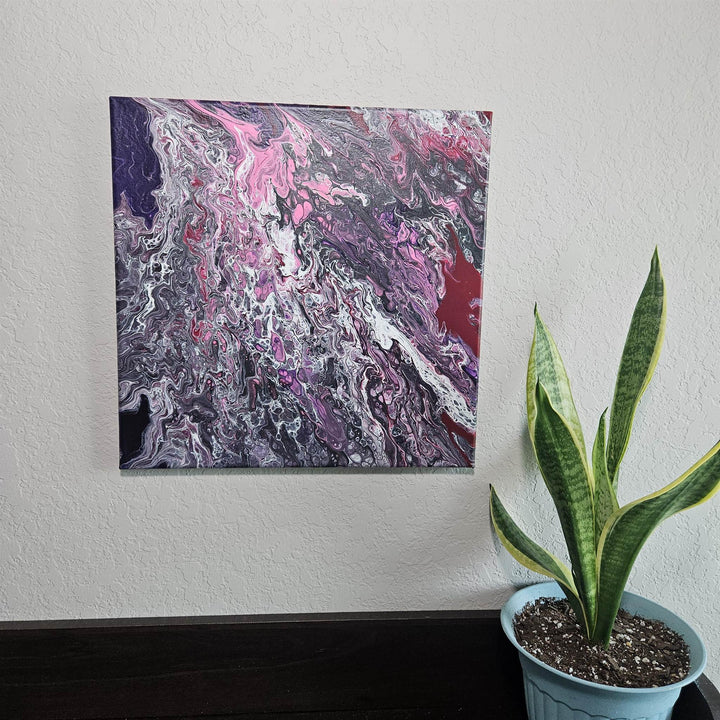 Swirly Cells – 14x14 Acrylic Pour Canvas Painting displayed on a wall beside a potted snake plant, showcasing its bold black, pink, and purple swirls.